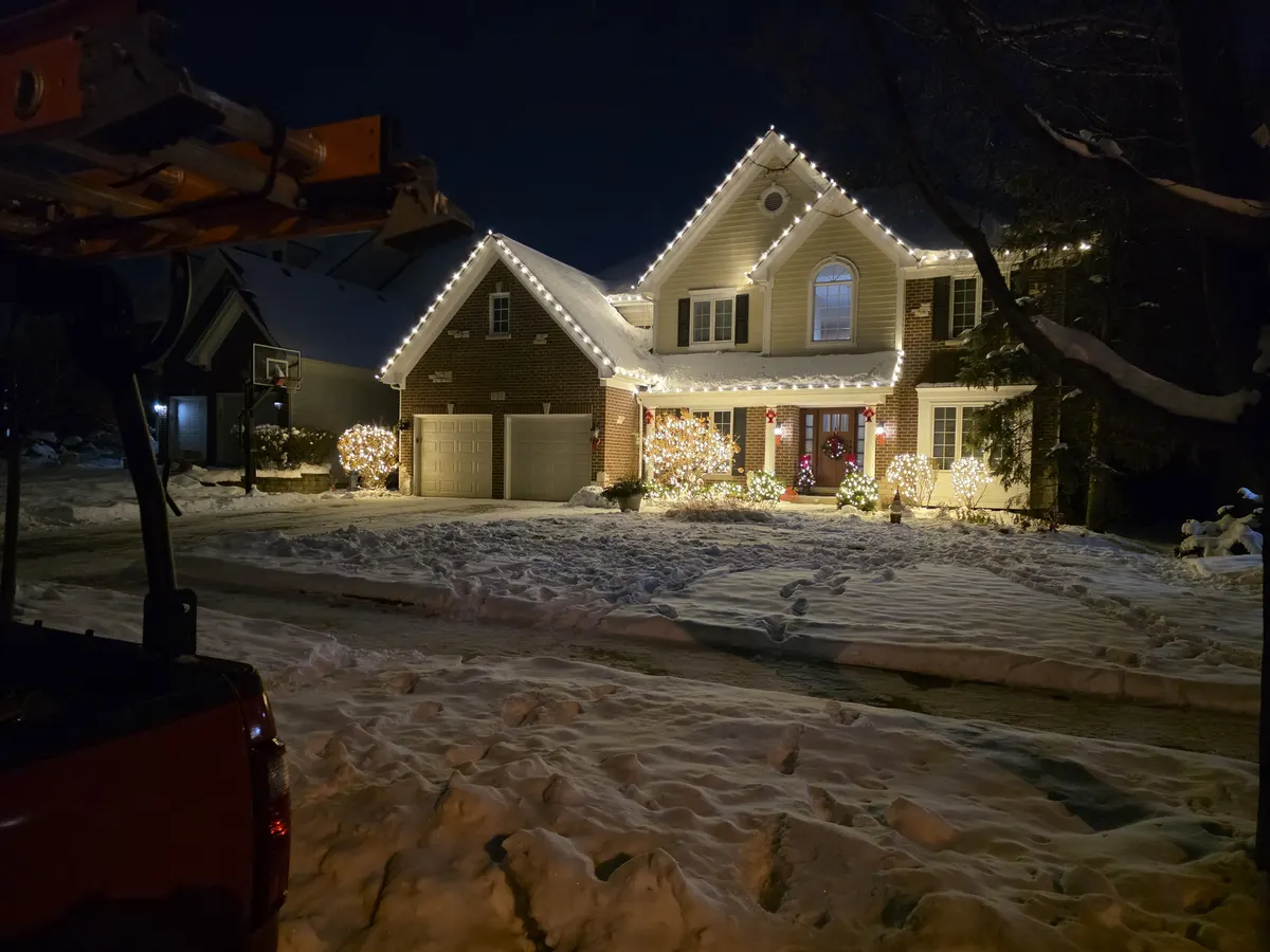 Roofline Christmas lights and lit bushes on a home in Westmont, IL