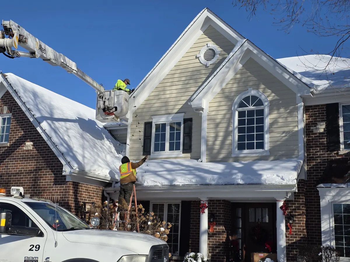 Crew installing snowy roofline Christmas lights in Westmont, IL